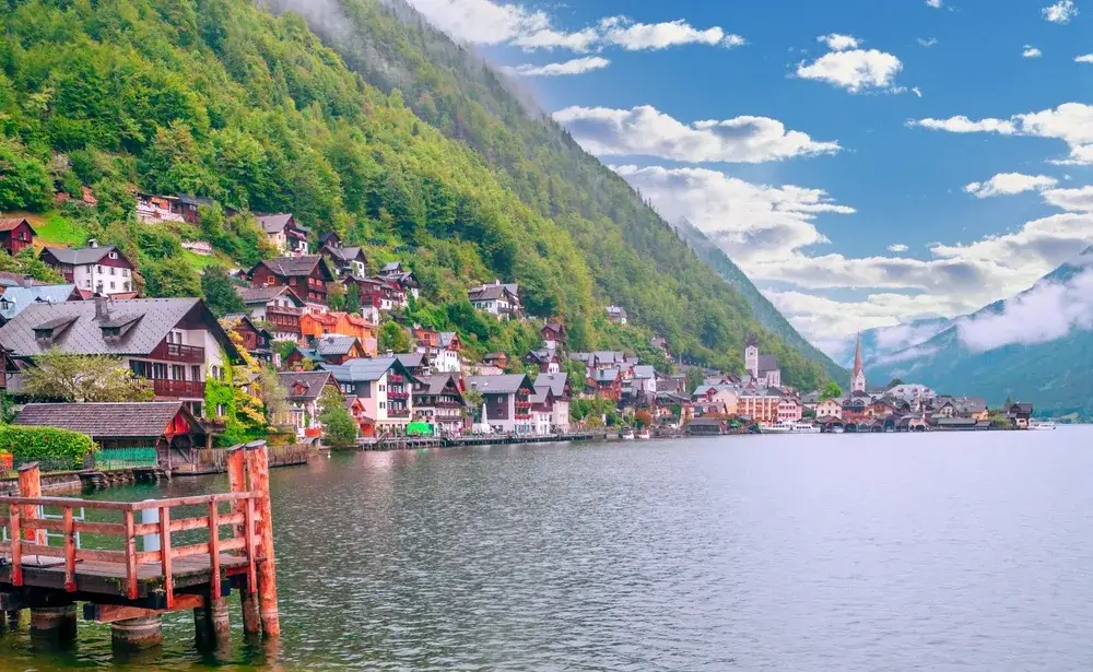 Little lakeside town of Alpbach pictured with homes overlooking the water and clouds low overhead in the valley as a top pick for the best places to visit in Austria