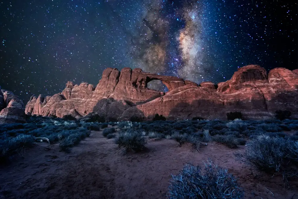 The Milky Way shining brightly over the Window of Arches National Park during the best time to go to Moab