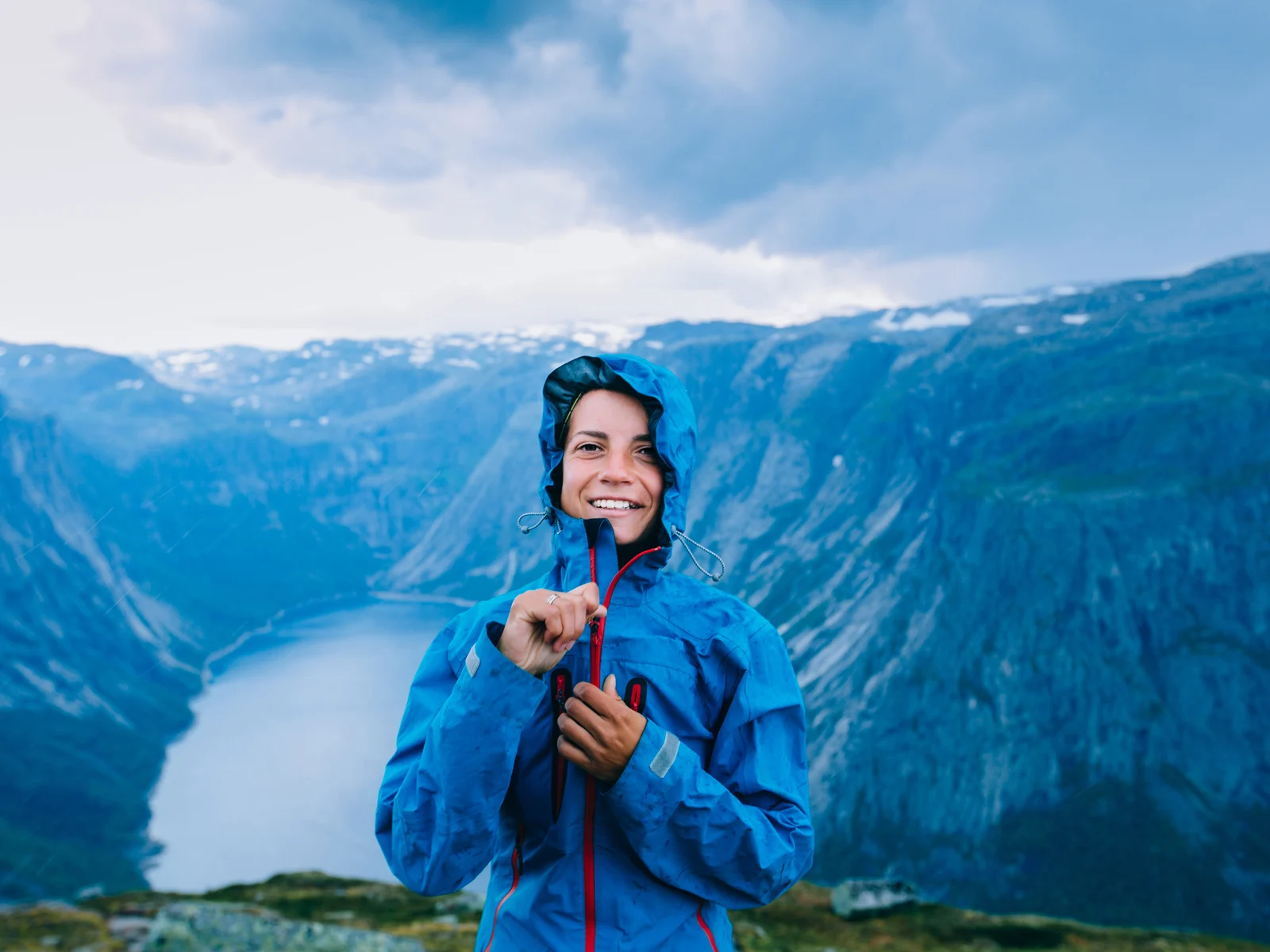 Happy woman zip up blue sportive jacket before rain during the worst time to visit Norway