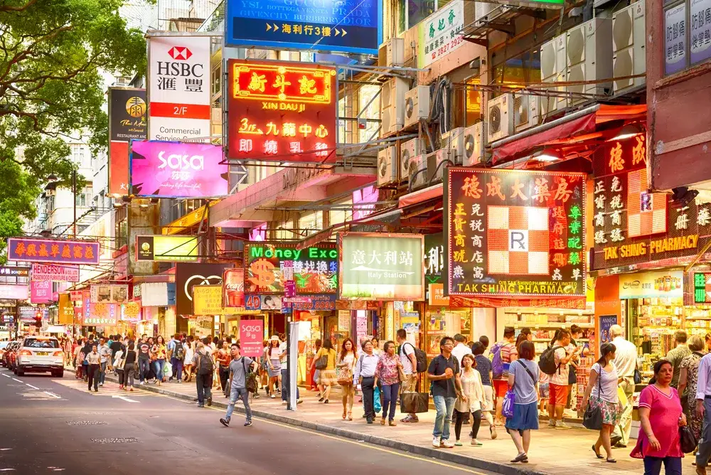 Very cool view of all of the neon lights in the downtown area with pedestrians walking along during the best time to visit Hong Kong