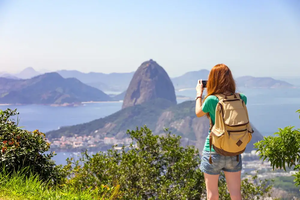 Girl taking a phone photo of Pao de Acucar to help answer is Brazil Safe to Visit