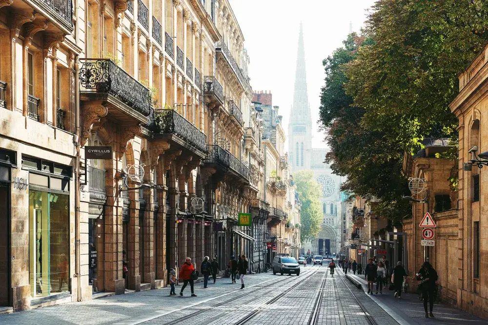 Empty street in Bordeaux, France pictured on a foggy day with the church's tower in the distance, as seen through the haze