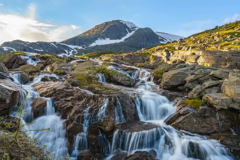 View of distant mountains and waterfalls flowing in Stora Sjöfallet National Park indicating why you should visit Sweden