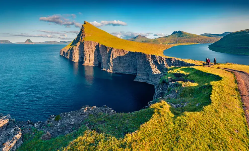 Aerial drone shot of people walking along a path near Sorvagsvatn Lake in Vagar during the cheapest time to visit Denmark