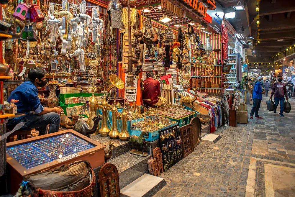 Man sits in a chair while he tends to his market in Mutrah Souq in Muscat during the best time to visit Oman