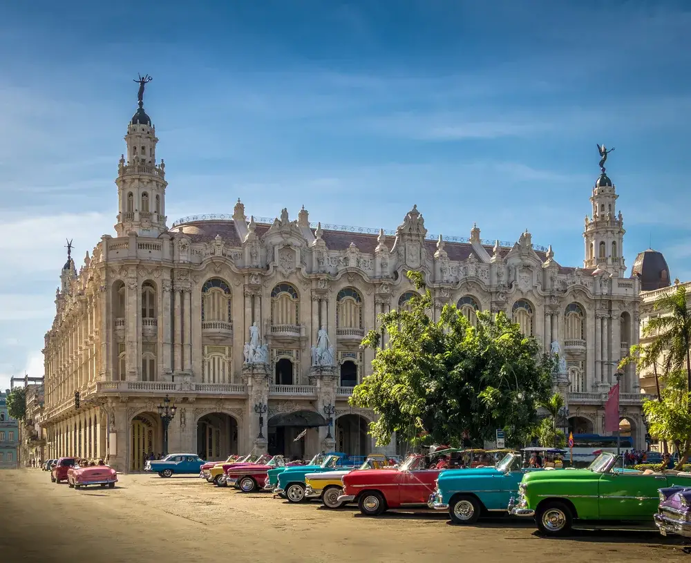 Gran Teatro in Havana pictured with bright-colored cars outside in the street for a post titled Is Cuba Safe to Visit