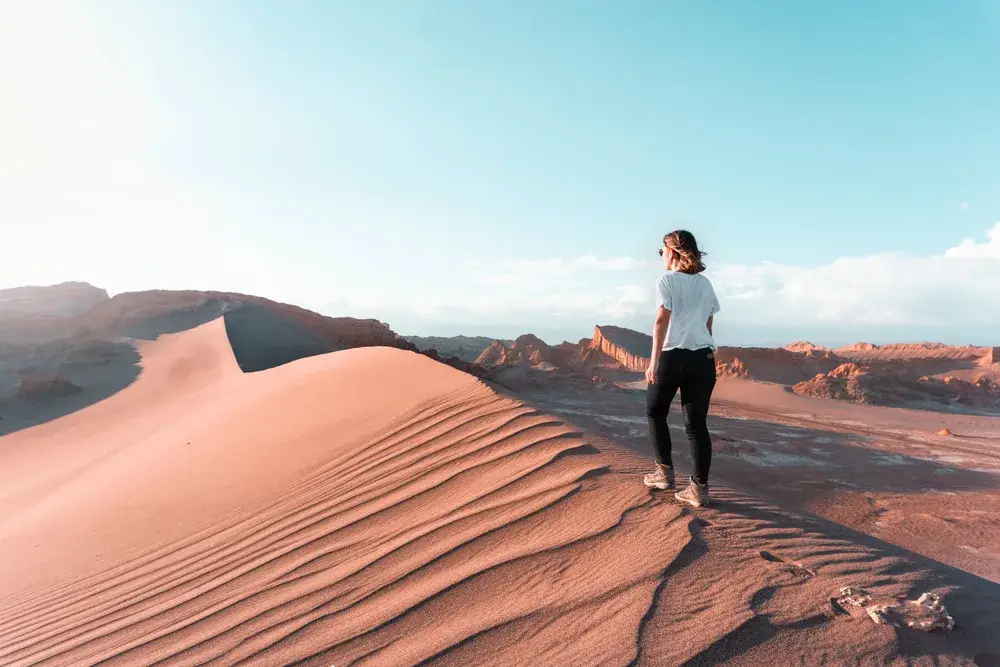 Pretty young woman traversing the sand dunes alone in Chile