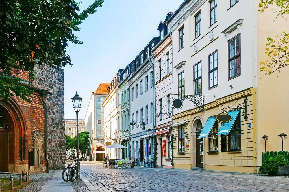 Cozy street in Berlin pictured with a bicycle leaning on a light post for a piece on is Germany Safe to Visit