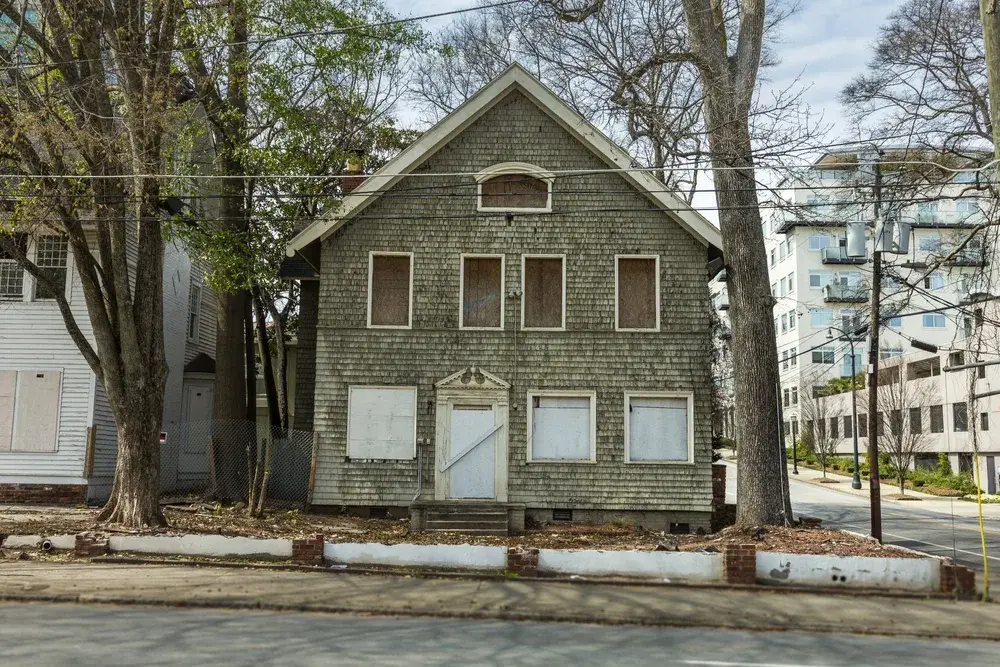 Boarded up house pictured off the street in an industrial part of town for a piece titled Is Georgia Safe to Visit