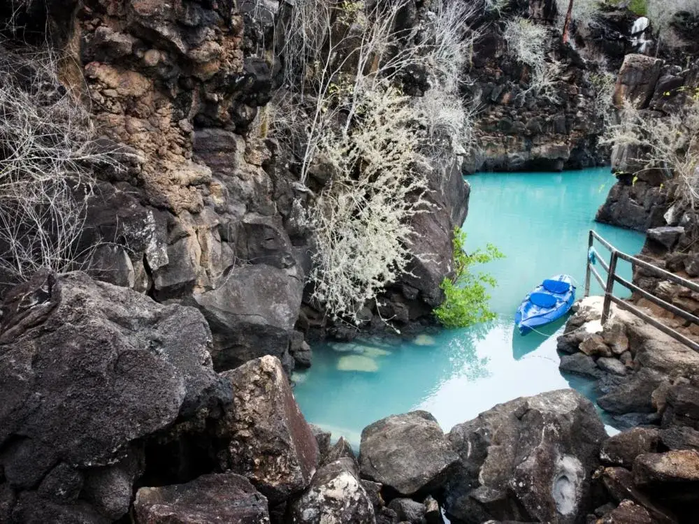 Kayak floating on a light blue river between rocks during the best time to visit Ecuador