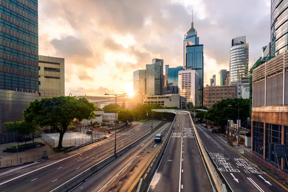 Image of an empty street in Hong Kong pictured with skyscrapers in the background and a single car driving down the street