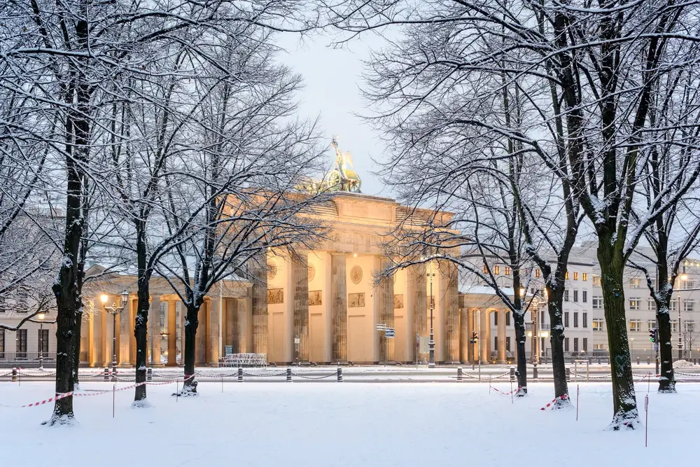 Tiergarten and Brandenburg Gate covered in snow with trees during the cheapest time to visit Berlin