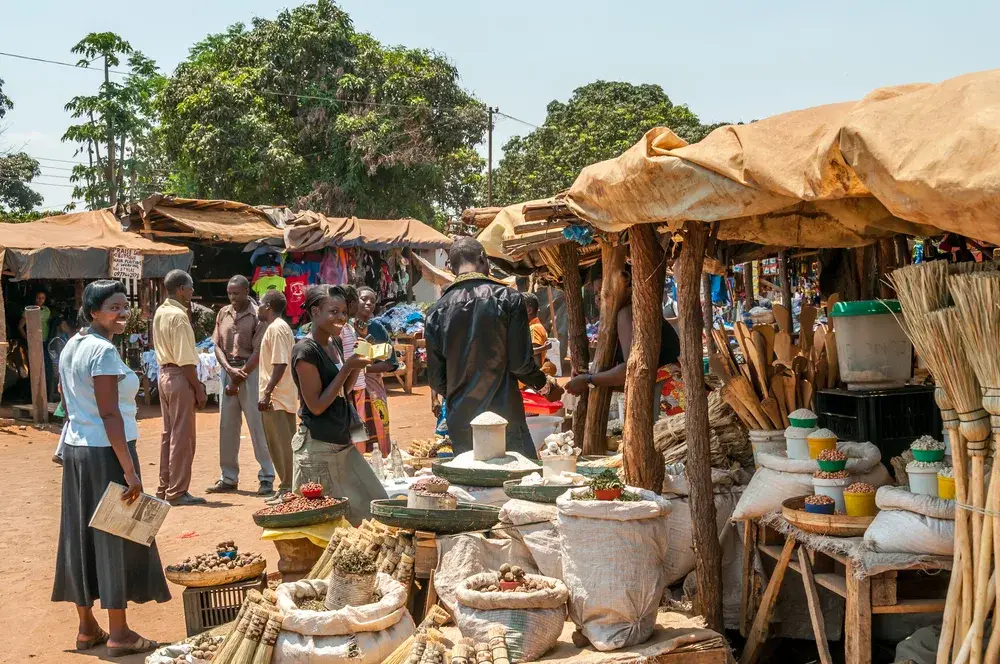 For a piece titled Is Zambia Safe to Visit, pictured are friendly locals interacting with each other and visitors to their quaint little shops while everyone smiles