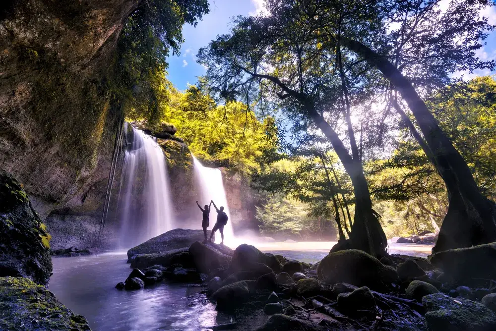 Young couple exploring the Heo Suwat Waterfall in Khao Yai National Park, a top pick for the best places to visit in Thailand