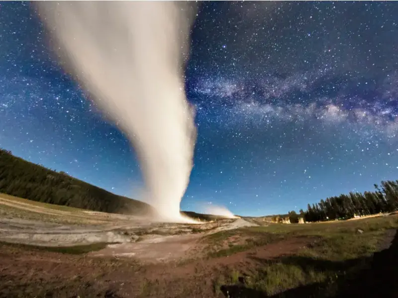 Amazing night view of Old Faithful erupting during the best time to visit Yellowstone