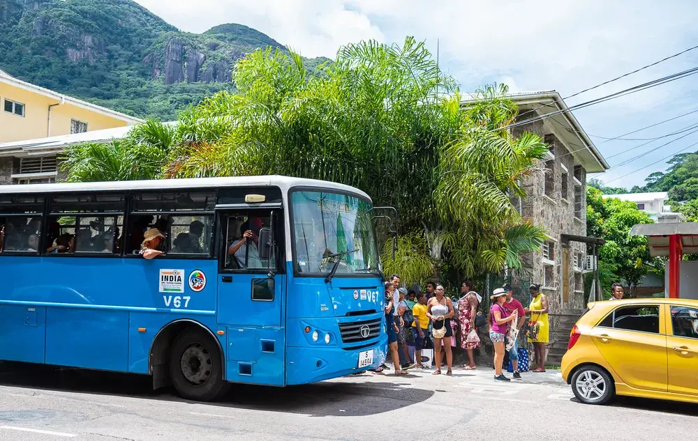 Blue bus and yellow taxi pictured outside of a town square for a piece titled is Seychelles Safe to Visit