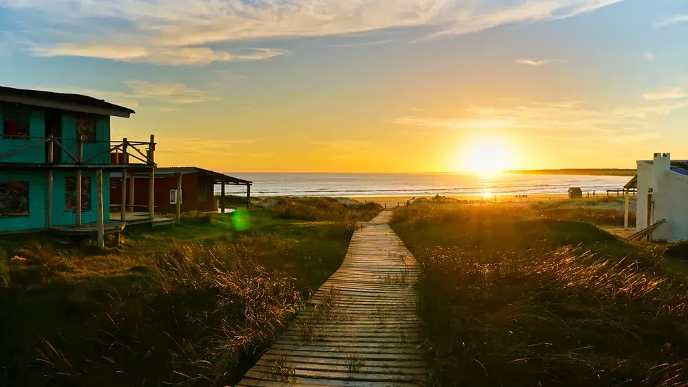 Sun setting over the ocean and illuminating the sky with a bright orange glow during the cheapest time to visit Uruguay