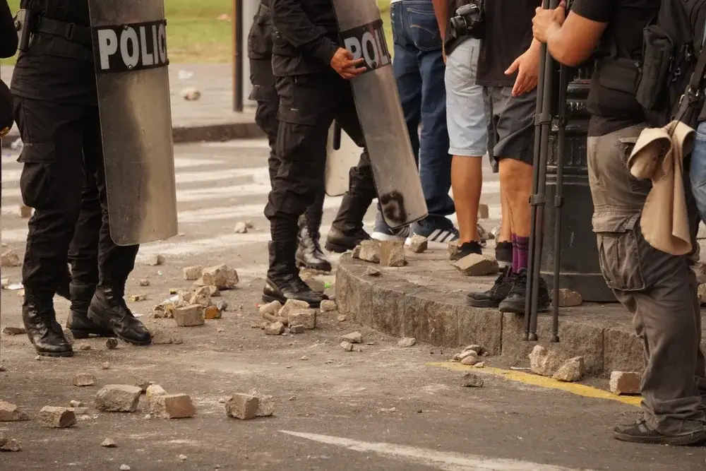 Protesters in Lima, Peru pictured next to police with shields for a piece on is South America safe to visit