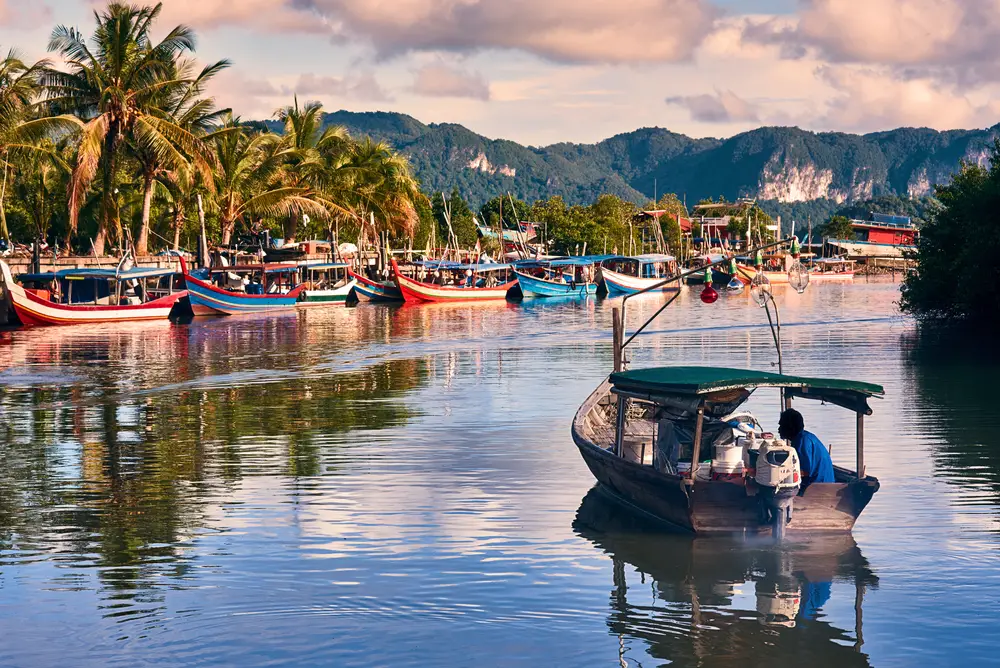 Fisherman driving a boat on the river in the small Malaysian fishing town of Langkawi Island for a piece titled Is Malaysia Safe to Visit