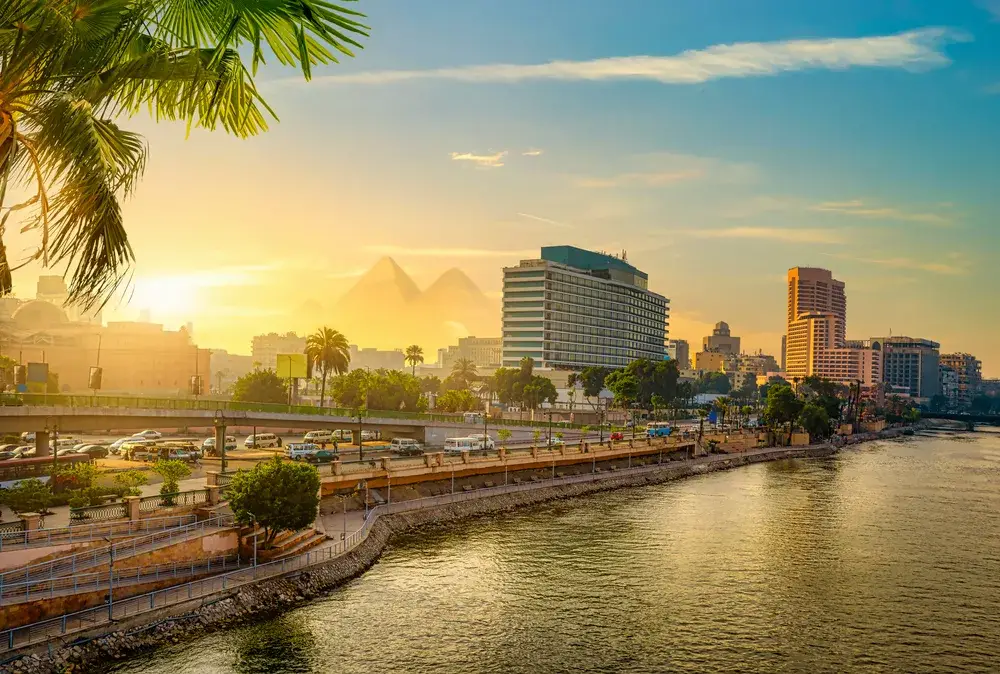 Pyramids in the background of the cityscape of Cairo, as seen from a boat on the Nile during the best time to visit Cairo