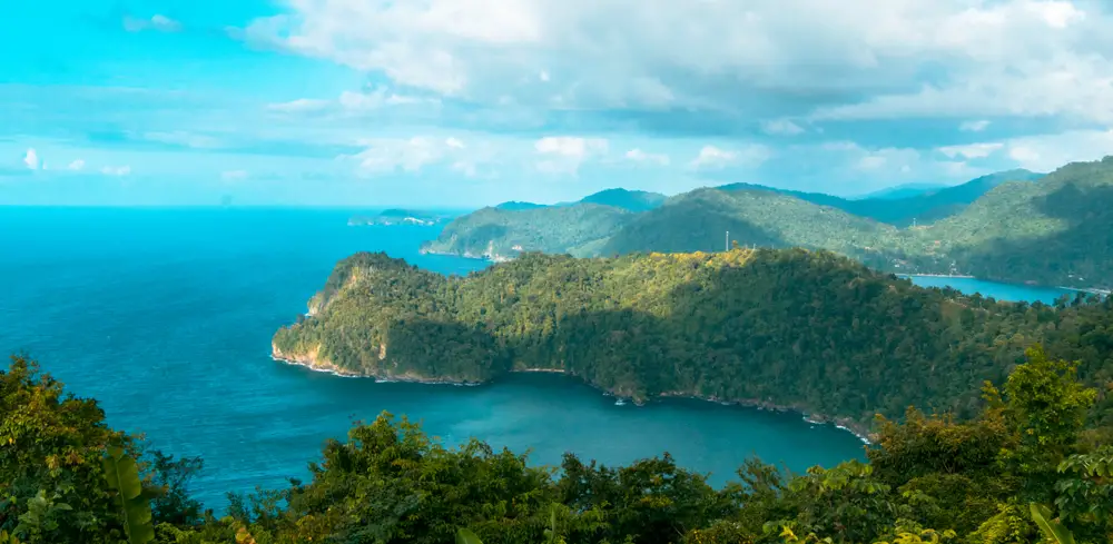 Maracas Beach lookout over the sea with blue cloudy skies overhead and mountains in the background during the least busy time to visit Trinidad