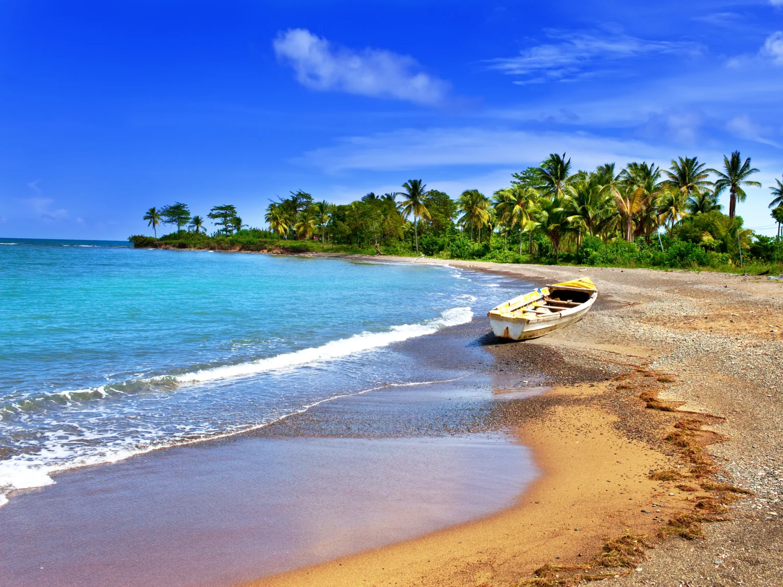 Boat abandoned on one of the best beaches in Jamaica on a clear blue sky day