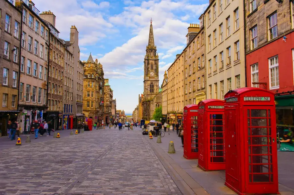 Empty street in Edinburgh pictured during the least busy time to visit with a church in the background and shops and homes on either side of the walking path