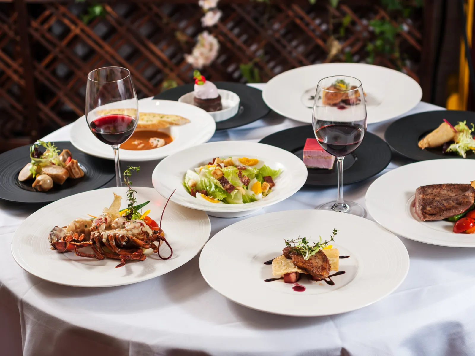 A bunch of French food on white plates on a fancy table below a bottle of wine